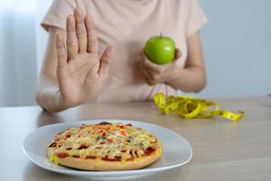 mulheres de corpo magro escolhem durante alimentos saudáveis e junk food, mulheres escolhem maçã verde para dieta. boa comida saudável. perda de peso, equilíbrio, controle, redução de gordura, baixas calorias, rotinas, exercícios. foto