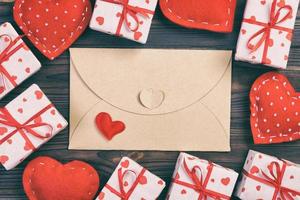 correio de envelope com coração vermelho e caixa de presente sobre fundo escuro de madeira. cartão de dia dos namorados, amor ou conceito de saudação de casamento foto