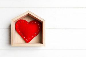 vista superior do coração têxtil vermelho em uma casa em fundo de madeira. conceito de lar doce lar. Dia dos Namorados foto