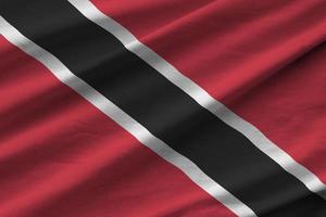 bandeira de trinidad e tobago com grandes dobras acenando perto sob a luz do estúdio dentro de casa. os símbolos e cores oficiais no banner foto