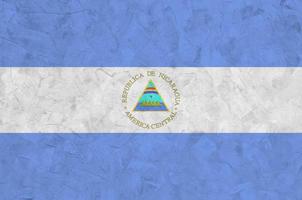 bandeira da nicarágua retratada em cores de tinta brilhante na parede de reboco em relevo antigo. banner texturizado em fundo áspero foto