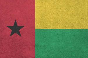 bandeira da guiné bissau retratada em cores brilhantes de tinta na parede de reboco em relevo antigo. banner texturizado em fundo áspero foto