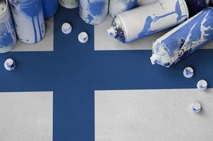 bandeira finlandesa e algumas latas de spray aerossol usadas para pintura de grafite. conceito de cultura de arte de rua foto