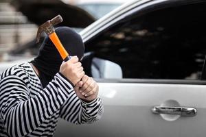 ladrão de carros sequestrar e roubar ou roubar dinheiro no carro e quebrar a janela da porta do carro sem alarme de carro trabalho criminoso ilegal e violento foto