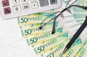 Fã de contas de 50 rublos bielorrussos e calculadora com óculos e caneta. empréstimo de negócios ou conceito de temporada de pagamento de impostos foto