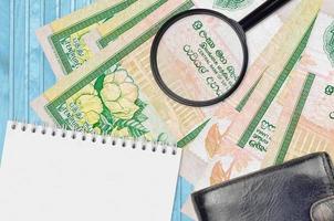 notas de 10 rúpias do Sri Lanka e lupa com bolsa preta e bloco de notas. conceito de dinheiro falso. procure diferenças nos detalhes das cédulas de dinheiro para detectar falsos foto
