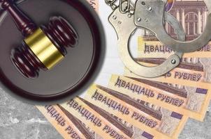 Notas de 20 rublos bielorrussos e martelo de juiz com algemas policiais na mesa do tribunal. conceito de julgamento judicial ou suborno. evasão fiscal foto