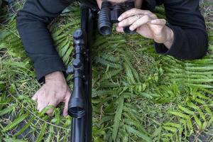 homem de vista superior com binóculos e rifle no chão de grama foto