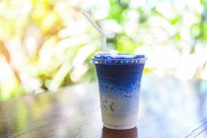 suco de ervilha borboleta ou chá de ervas de flor de ervilha azul com leite para beber em fundo de madeira foto