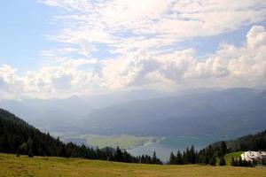 viajar para sankt-wolfgang, áustria. a vista sobre a floresta verde e um prado com um lago e as montanhas ao fundo. foto