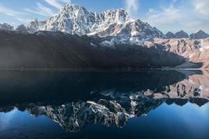 montanha coberta de neve e seu reflexo no lago de águas paradas chamado lago gokyo. localizada nas profundezas do himalaia, na fronteira do nepal, a tranquila vila de gokyo está estabelecida ao redor do lago. foto