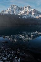 montanha coberta de neve e seu reflexo no lago de águas paradas chamado lago gokyo. localizada nas profundezas do himalaia, na fronteira do nepal, a tranquila vila de gokyo está estabelecida ao redor do lago. foto