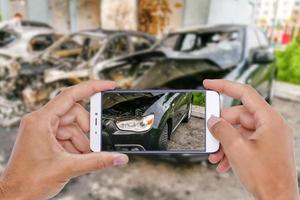 acidente de carro danificado com a mão usando smartphone tirando foto