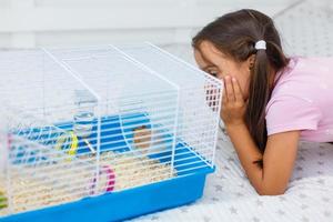 menina segura gaiola para hamster em casa foto
