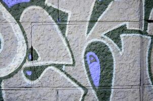 fragmento de desenhos de grafite. a parede antiga decorada com manchas de tinta no estilo da cultura da arte de rua. textura de fundo colorido em tons de roxo foto