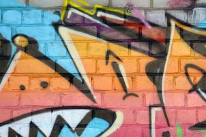 fragmento colorido abstrato de pinturas de grafite na parede de tijolos antigos. composição de arte de rua com partes de letras selvagens e manchas multicoloridas. textura de fundo subcultural foto