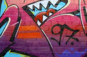 fragmento colorido abstrato de pinturas de grafite na parede de tijolos antigos. composição de arte de rua com partes de letras selvagens e manchas multicoloridas. textura de fundo subcultural foto