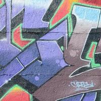 fragmento de desenhos de grafite. a parede antiga decorada com manchas de tinta no estilo da cultura da arte de rua. textura de fundo colorido em tons de roxo foto