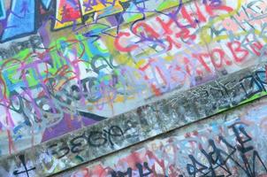 fragmento de tags de graffiti. a velha parede está estragada com manchas de tinta no estilo da cultura da arte de rua foto
