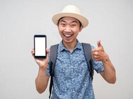 homem asiático viajante mostra telefone celular para reserva e polegar para cima isolado foto