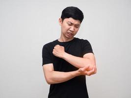 homem asiático camisa preta sente dor no cotovelo isolado foto