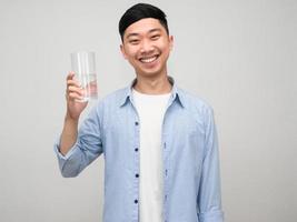 homem asiático positivo camisa azul segurar copo de água sorriso feliz isolado foto