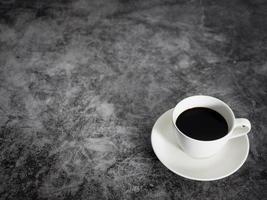 xícara branca de café preto no espaço de cópia de mesa de chão escuro foto