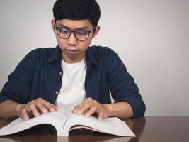 homem asiático usa óculos aprendendo livro de texto sobre a mesa foto