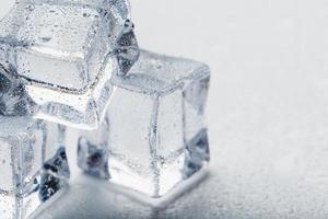 cubos de gelo na forma de uma pirâmide com água cai de perto - em macro sobre um fundo branco. foto