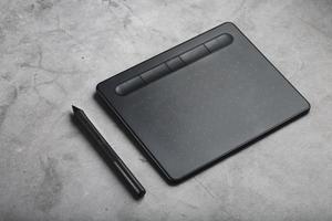 tablet gráfico com uma caneta sobre um fundo cinza, o trabalho de um designer, artista e fotógrafo. A vista do topo foto