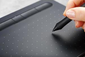 caneta com um tablet gráfico nas mãos do designer, close-up. gadget para arte e trabalho.