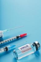 seringas e ampola com a vacina contra o vírus de doenças em um fundo azul. foto