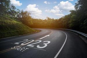 feliz ano novo 2023,2023 simboliza o início do ano novo. a carta começa o ano novo de 2023 na estrada na estrada da rota da natureza tem ecologia de ambiente de árvore ou conceito de papel de parede verde. foto