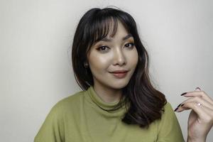 um rosto alegre de beleza da jovem modelo asiática vestindo top verde. tratamento facial de beleza para a pele, spa, conceito de saúde feminina. foto
