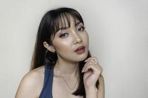 um rosto alegre de beleza da jovem modelo asiática vestindo top verde-azulado. maquiagem skincare beleza tratamento facial, spa, conceito de saúde feminina.