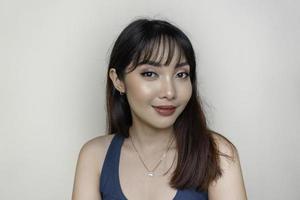 um rosto alegre de beleza da jovem modelo asiática vestindo top verde-azulado. maquiagem skincare beleza tratamento facial, spa, conceito de saúde feminina.