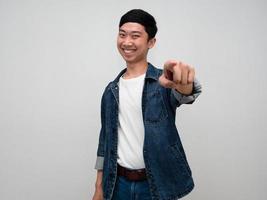 homem asiático alegre camisa jeans gesto dedo apontado por escolher você isolado foto