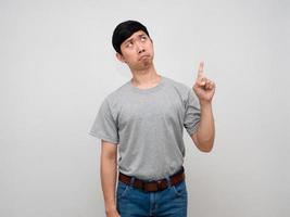 homem asiático camisa cinza em pé dedo apontado acima sente-se preocupado isolado foto