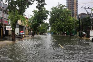 semarang, dezembro de 2022. algumas pessoas estão caminhando pela enchente que atingiu a área da estação de trem poncol e alguns moradores estão se preparando para evacuar. veículos atingiram a enchente foto