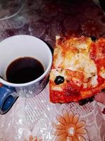 um pedaço de pizza com uma xícara de café foto