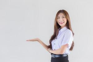 retrato de um estudante tailandês adulto em uniforme de estudante universitário. menina bonita asiática em pé para apresentar algo com confiança sobre fundo branco. foto