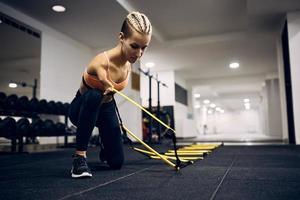 mulher atlética com deficiência usando escada de agilidade de pés durante o treinamento esportivo em uma academia. foto