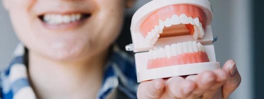 conceito de estomatologia, retrato parcial de menina com fortes dentes brancos, olhando para a câmera e sorrindo, dedos perto do rosto. closeup de jovem no dentista, estúdio, dentro de casa foto