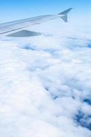 asa de um avião voando sobre nuvens brancas e céu azul foto