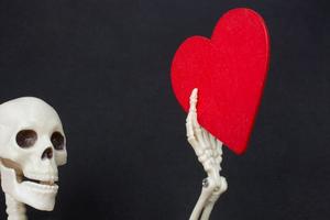 esqueleto artificial do corpo humano com um ícone de coração de papel na mão foto