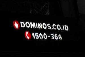 bekasi, indonésia em julho de 2022. logotipo da pizza do domino brilhando intensamente à noite contra o céu noturno escuro. foto