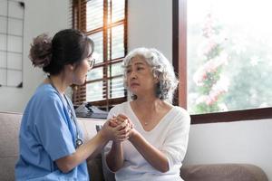 paciente feliz está segurando o cuidador por uma mão enquanto passa um tempo juntos. mulher idosa em casa de repouso e enfermeira. foto