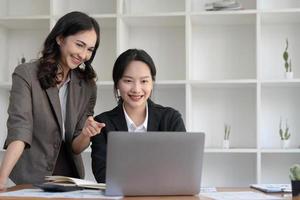 duas jovens empresárias asiáticas conversam, consultam, discutem o trabalho com a nova apresentação da ideia do projeto de inicialização analisam o plano de marketing e investimento no escritório. foto