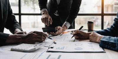 pessoas de negócios reunidas usando computador portátil, calculadora, notebook, papel gráfico do mercado de ações para planos de análise para melhorar a qualidade no próximo mês. conceito corporativo de discussão de conferência foto