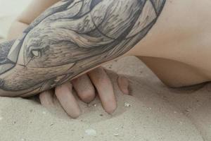 close-up jovem mulher nua com tatuagem na foto do conceito de praia de areia